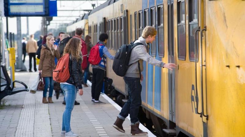 An image of Dutch people standing at a station and boarding a train from Nederlandse Spoorwegen (NS)